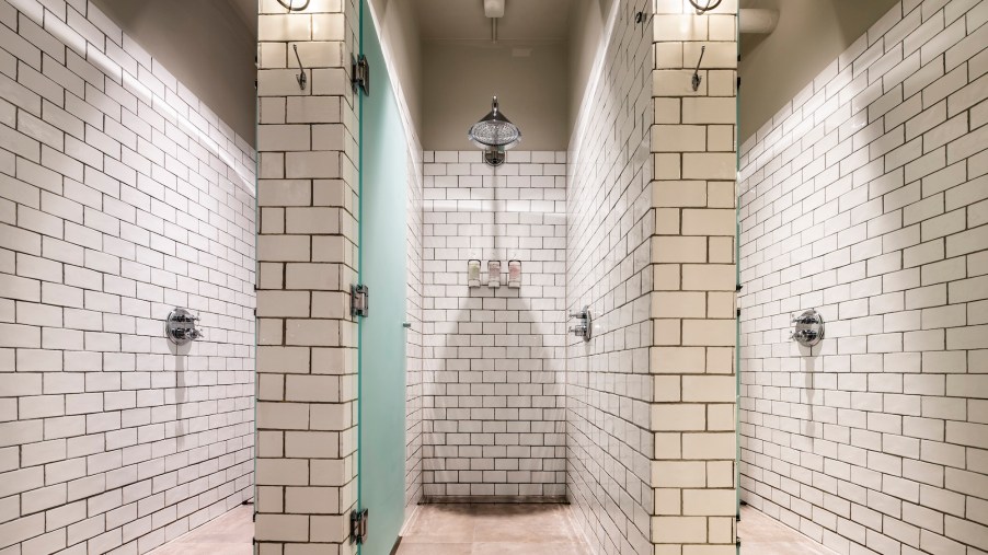 Gym showers with chic white subway tile walls and industrial lighting