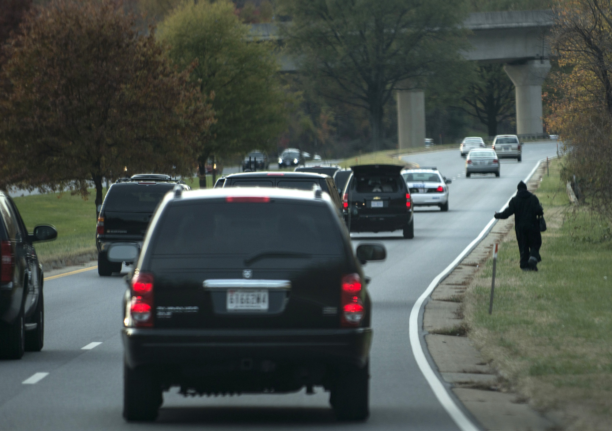 A hitchhiker walks on the side of the road as President Barack Obama's motorcade passes on the Suitland Parkway on November 10, 2012 in Suitland, Maryland.