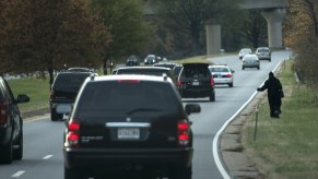 A hitchhiker walks on the side of the road as President Barack Obama's motorcade passes on the Suitland Parkway on November 10, 2012 in Suitland, Maryland.