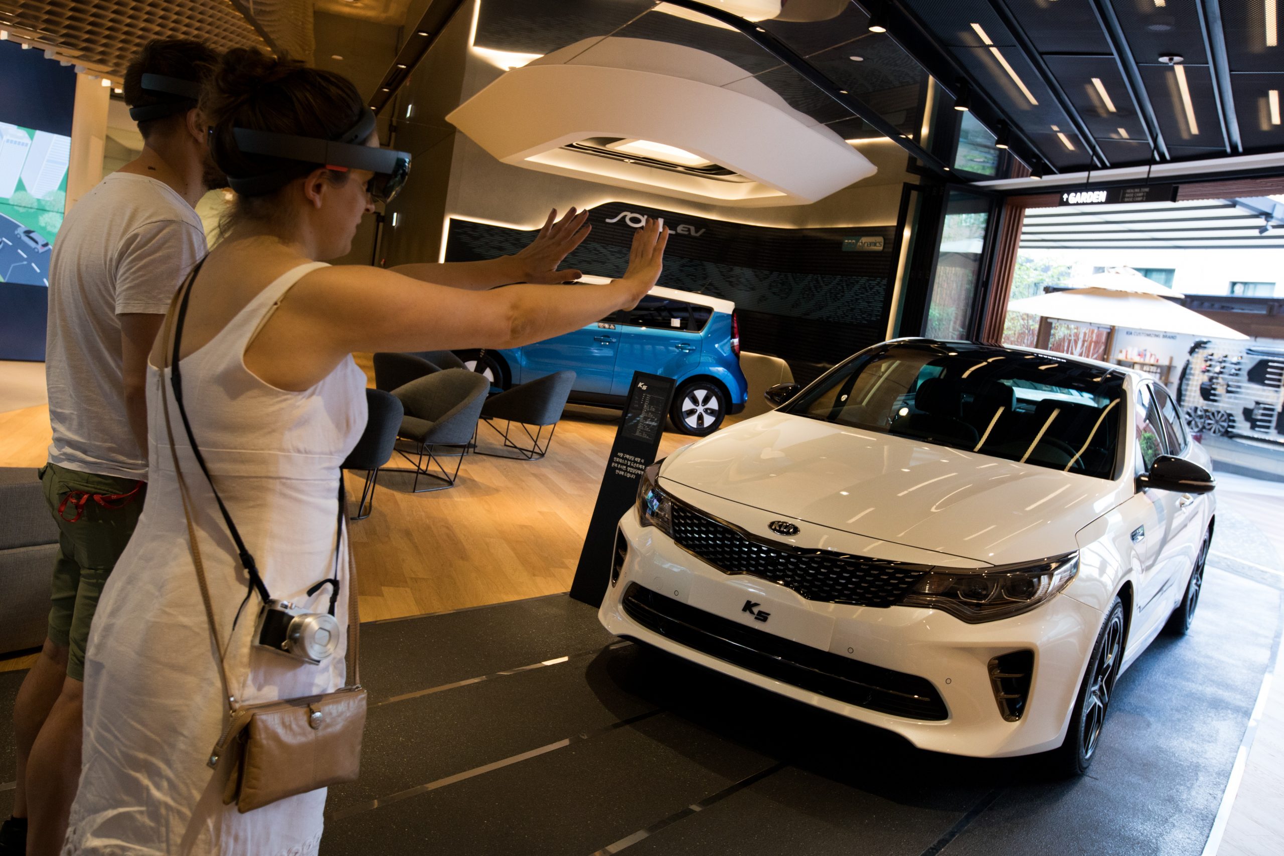 A customer tests out a HoloLens Virtual Reality headset to look at a Kia K5 at the dealership
