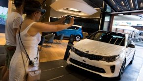 A customer tests out a HoloLens Virtual Reality headset to look at a Kia K5 at the dealership