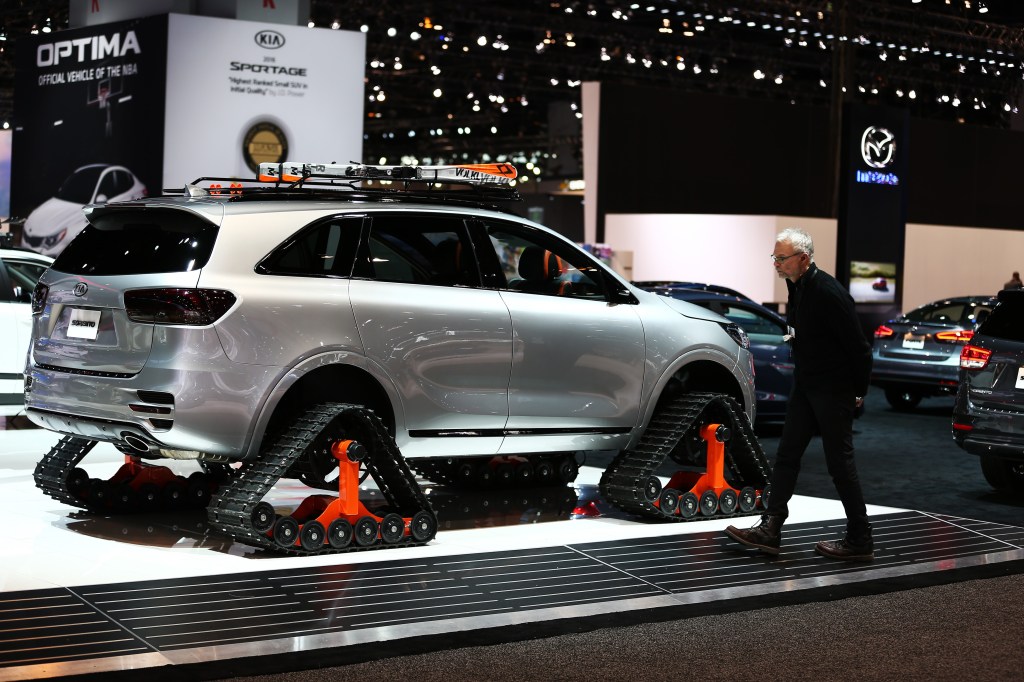 A silver Kia Sorento riding on snow tracks in an auto show booth