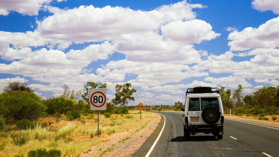 An SUV travels on the left-hand side of the road in the Australian outback