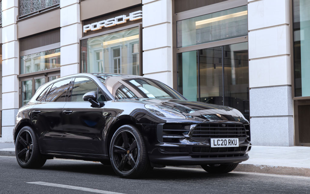 A black Porsche Macan sits outside a shop on the street in London
