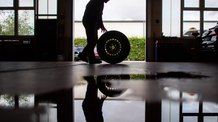 Mechanic rolling a wheel through the shop