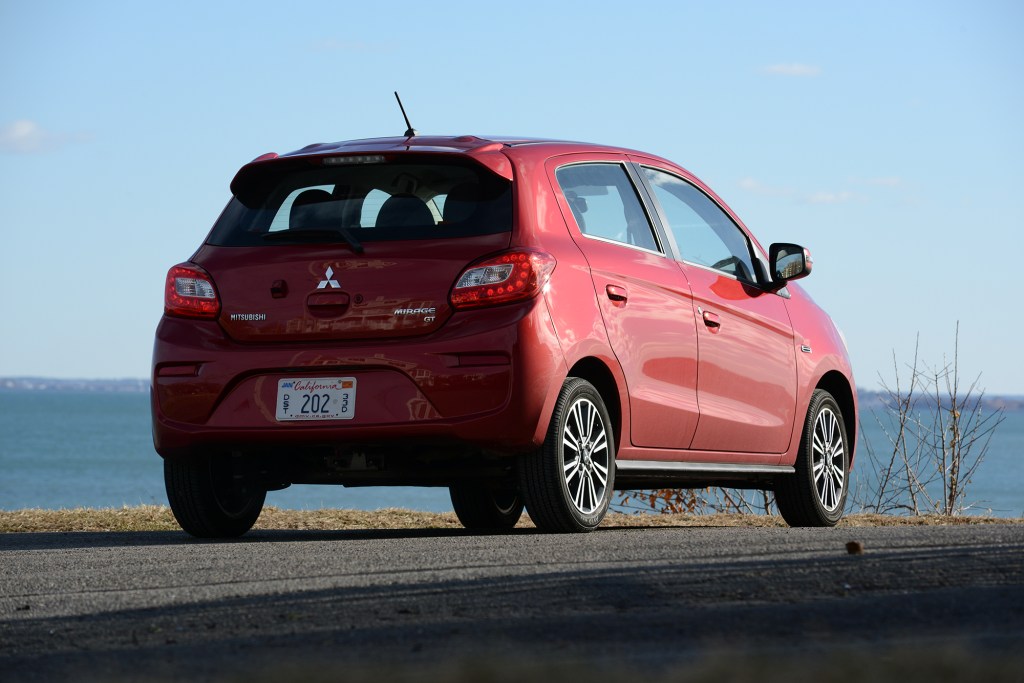 A red mitsubishi mirage parked by the water