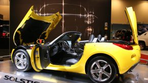 a yellow pontiac solstice sports car on display with the front and rear hatch open