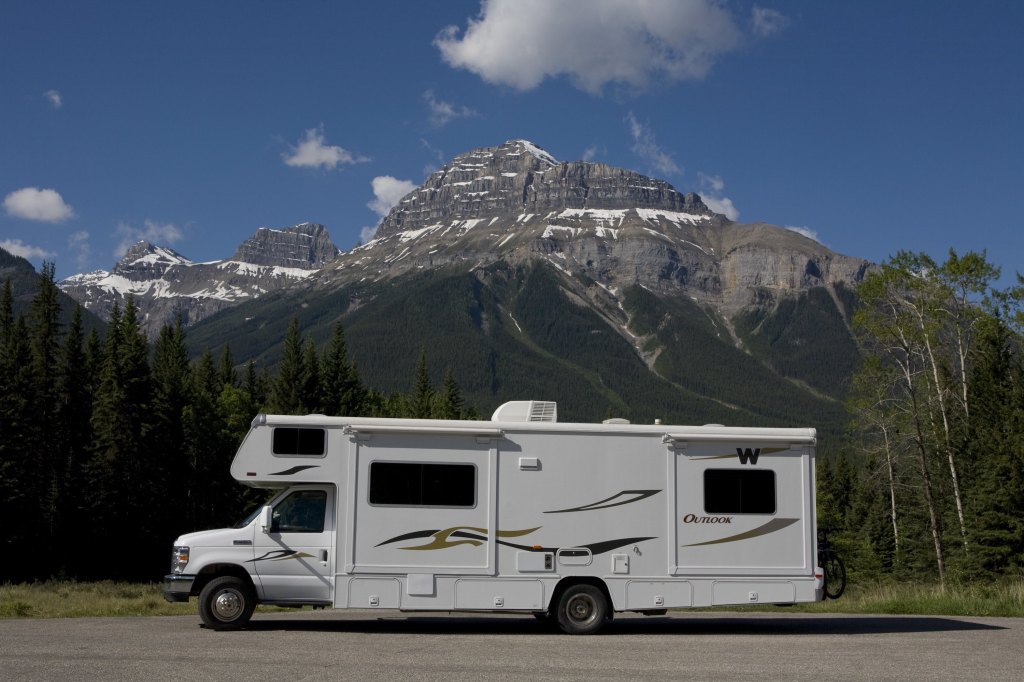 A large RV parked at the base of a mountain