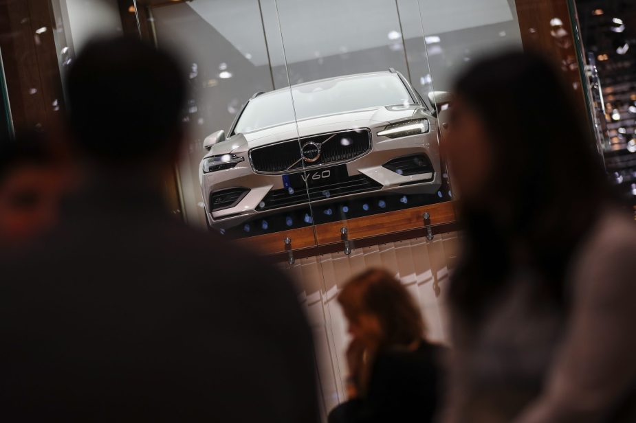 The Volvo V60 in silver sits in a booth at the Geneva Motor Show as spectators walk by