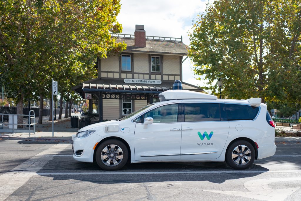 A white Waymo self-driving minivan on a city street