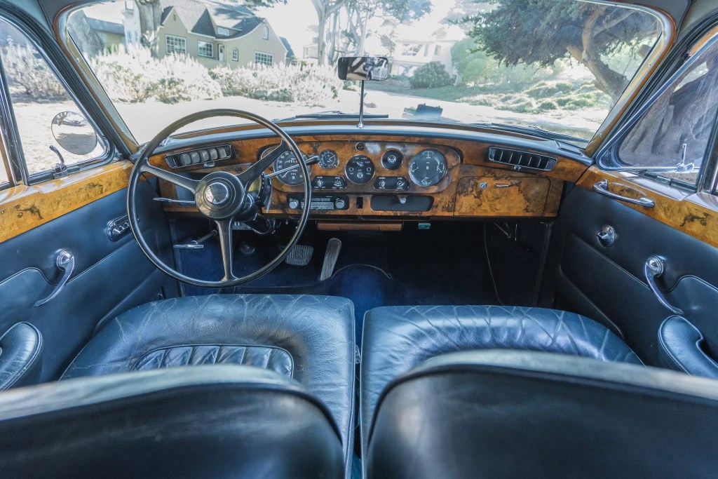 The blue-leather-upholstered and walnut-wood-trimmed front interior of a 1965 Rolls-Royce Silver Cloud III