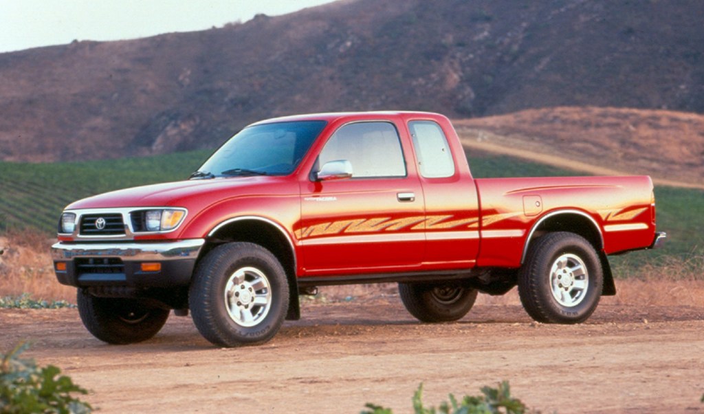 A red-with-gold-side-stripes 1995.5 Toyota Tacoma Xtracab SR5 in the desert