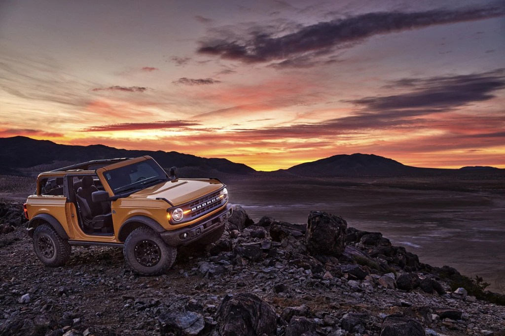 A yellow Ford Bronco off road at sunset