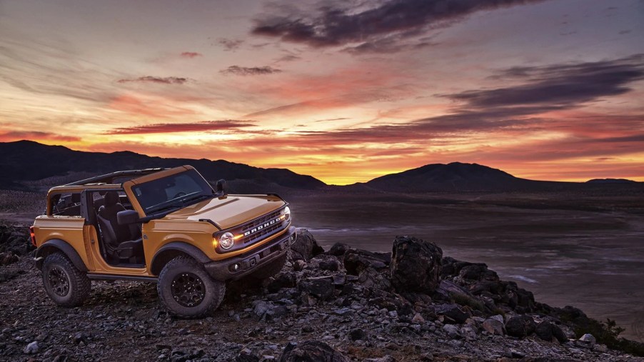 A yellow Ford Bronco off road at sunset