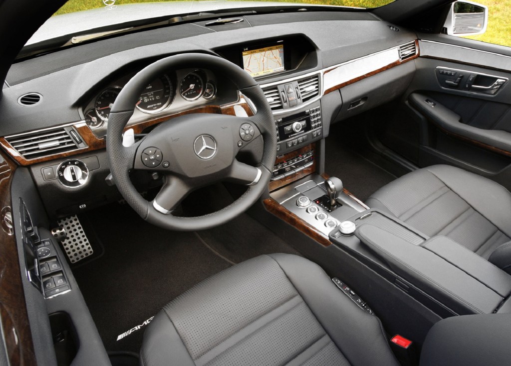 The black-leather front seats and wood-and-leather-trimmed dashboard of a 2010 Mercedes-Benz E63 AMG
