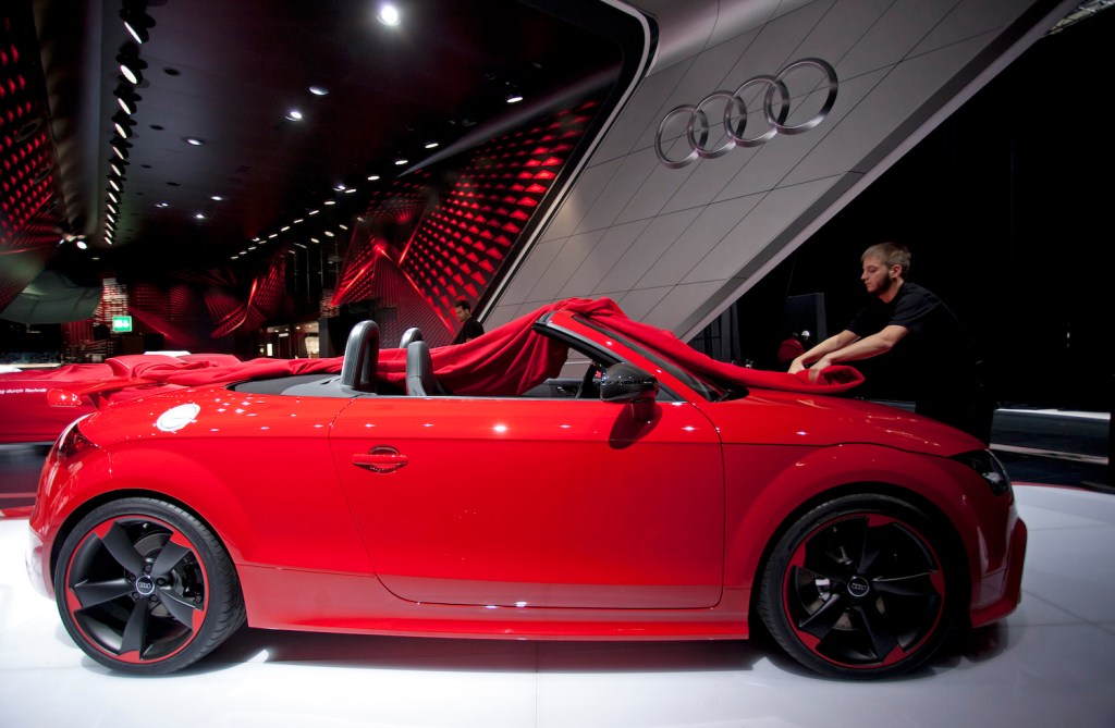 An employee unfurls the protective cover of an Audi AG TT automobile displayed on the company's stand ahead of the opening day of the Paris Motor Show in Paris, France, on Wednesday, Sept. 26, 2012. 