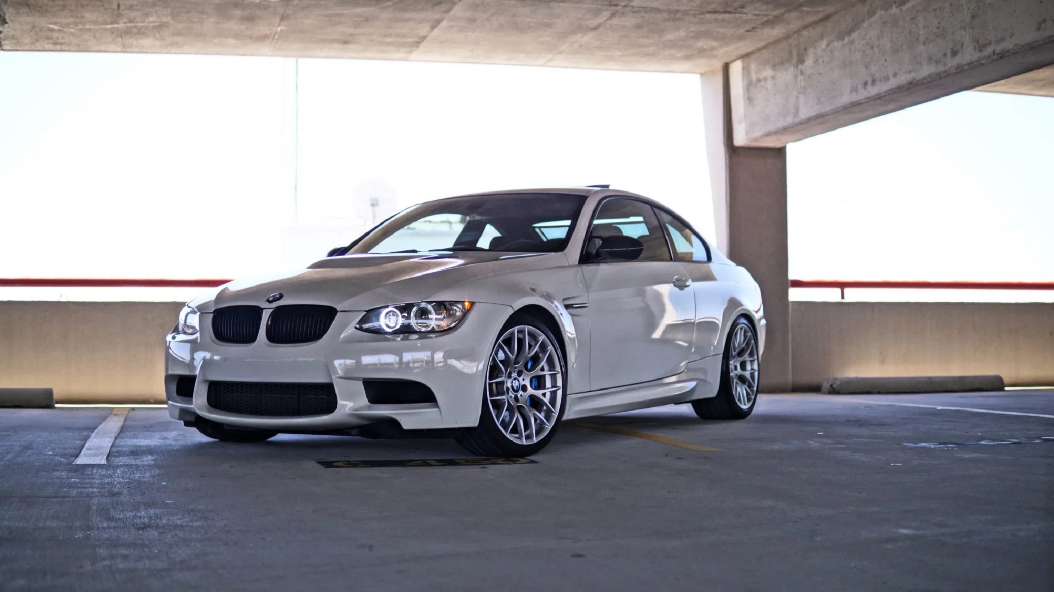 A white 2012 BMW M3 Competition Coupe in a parking garage