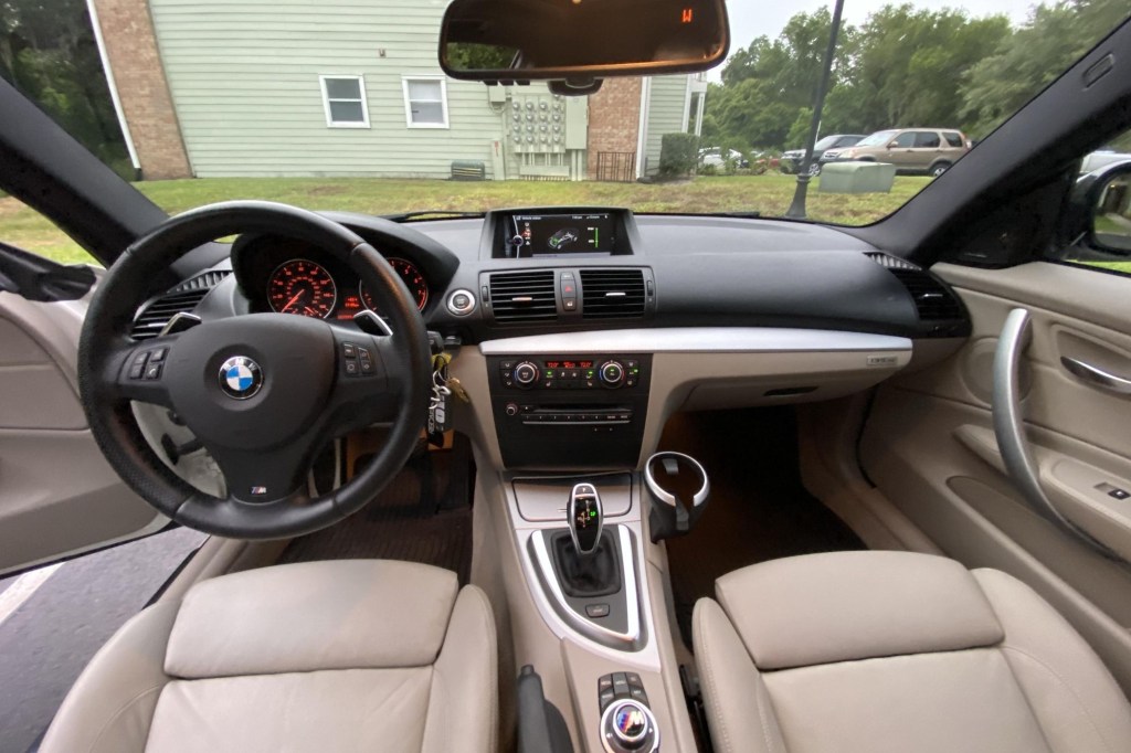 The tan-leather front seats and black dashboard of a 2013 BMW 135is Coupe