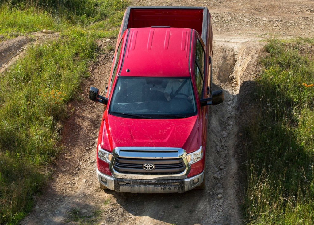 A red 2014 Toyota Tundra descents down a gravel path on a grassy hill