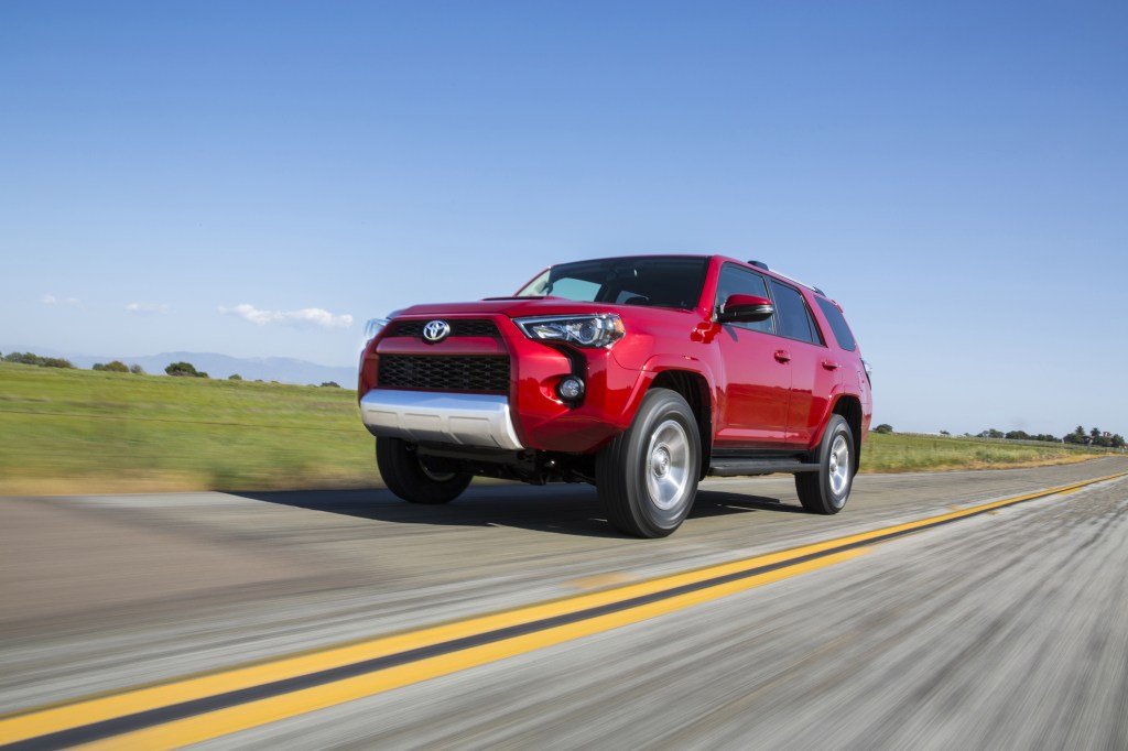 A red 5th Gen 4Runner rolling down a straight, empty road