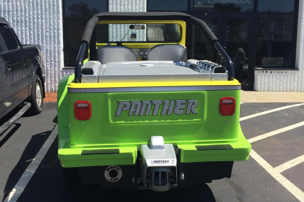 The rear view of a green-gray-and-yellow 2016 WaterCar Panther in a parking lot next to a black car