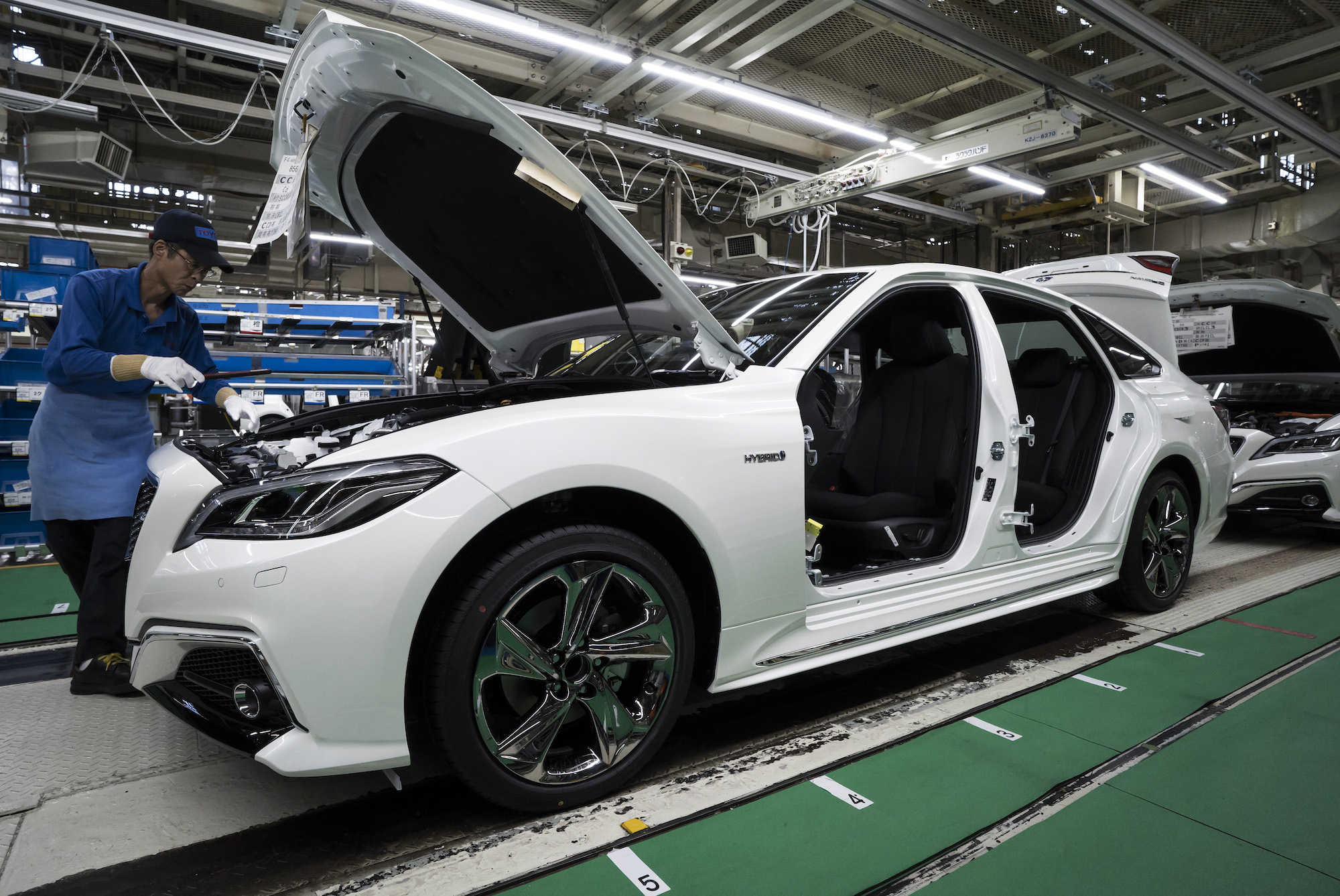 A worker assembles a white Toyota Crown sedan on the production line of the company's Motomachi factory on July 30, 2018, in Toyota, Japan
