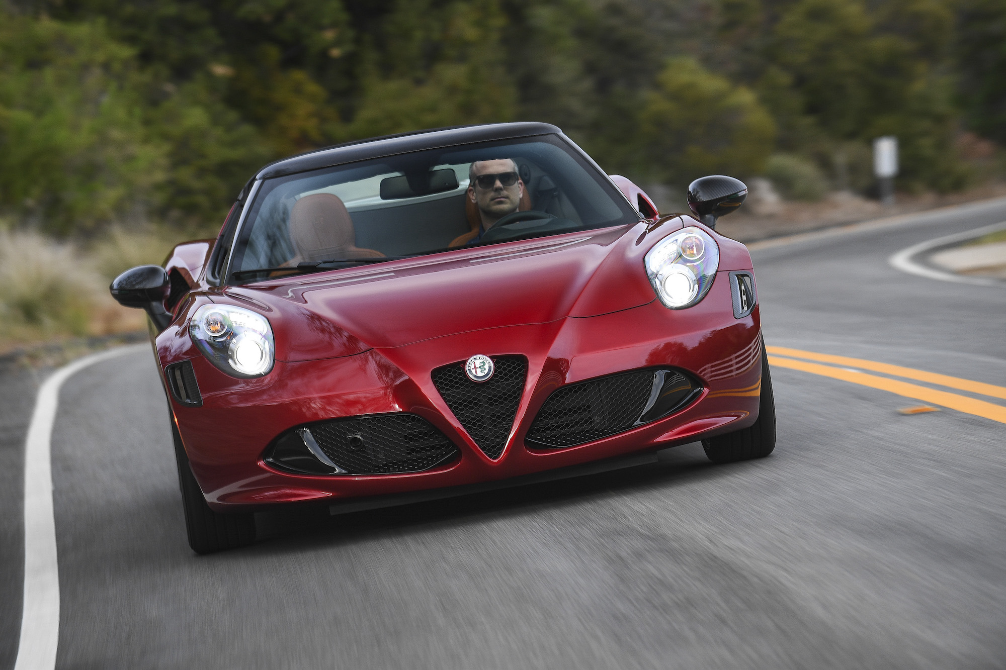 A dark-red 2020 Alfa Romeo 4C Spider 33 Stradale Tributo sports car travels on a winding highway