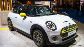 A white, yellow, and black 2020 Mini Cooper SE electric car on display at Brussels Expo in January 2020