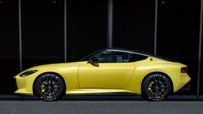 The side view of the yellow 2020 Nissan Z Proto Concept in front of a black building