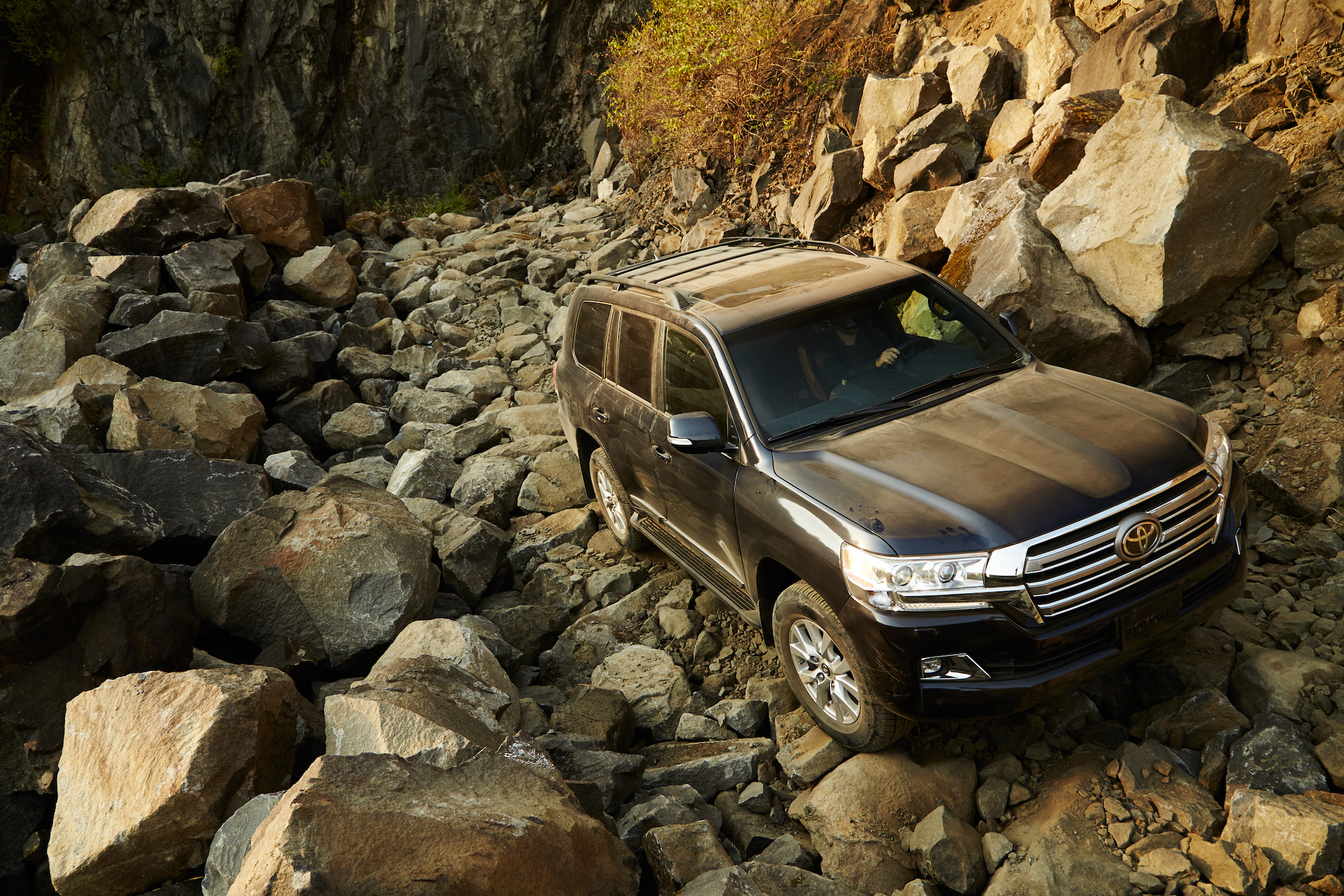 A dusty black 2020 Toyota Land Cruiser full-size SUV parked on a rocky mountainside