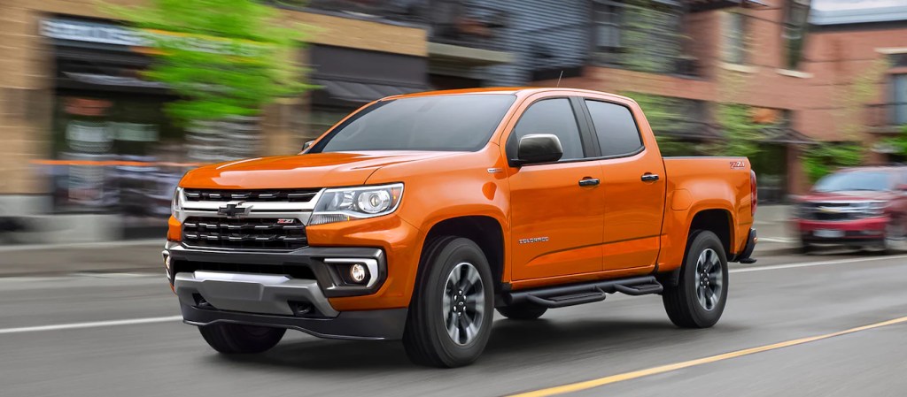 An orange Chevy Colorado pickup truck driving in the city