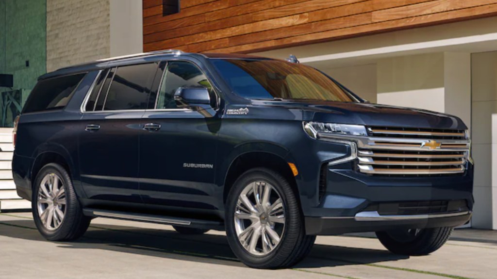 A blue 2021 Chevrolet Suburban SUV parked outside of a luxurious home.