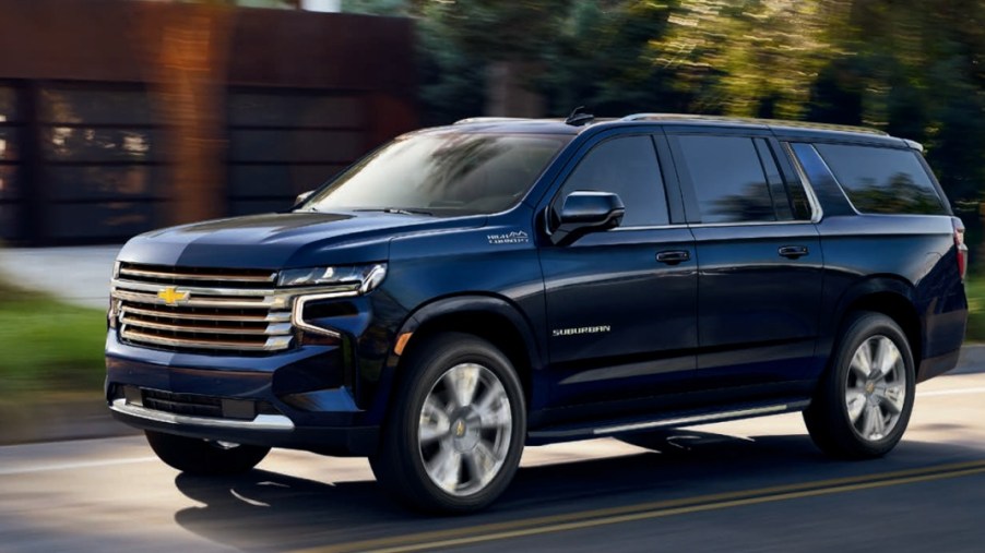 A blue 2021 Chevrolet Suburban full-size SUV is driving on the road.