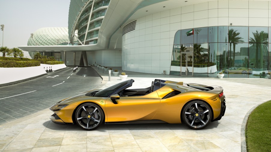 A yellow metallic 2021 Ferrari SF90 Spider parked outside a large white modern buiding