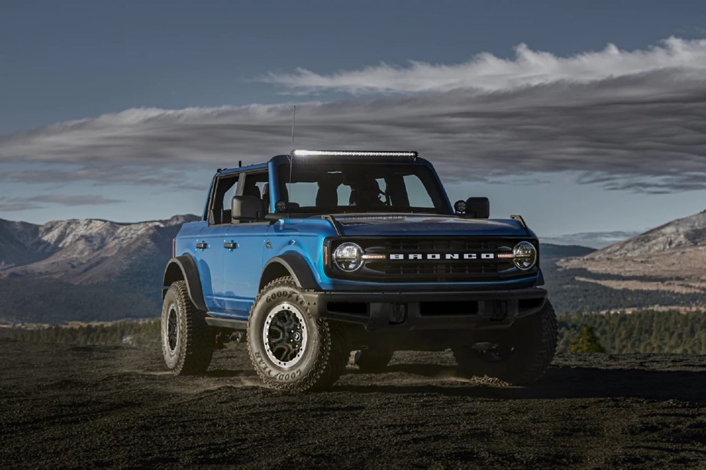 A blue 2021 Ford Bronco 4-Door Black Diamond with Sasquatch Package and light bar on a rocky mountain