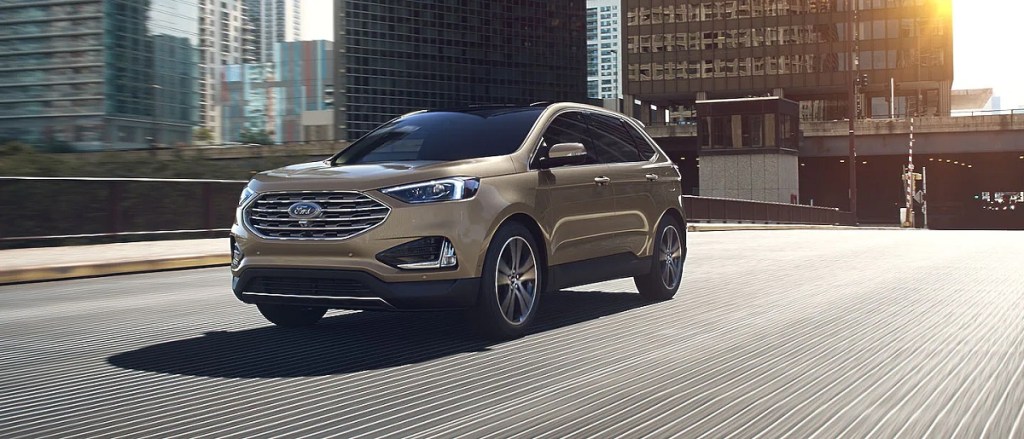 A gold 2021 Ford Edge travels over a bridge.