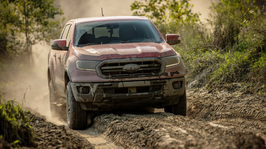 A mud-covered 2021 Ford Ranger Tremor Lariat compact pickup truck navigates an off-road trail