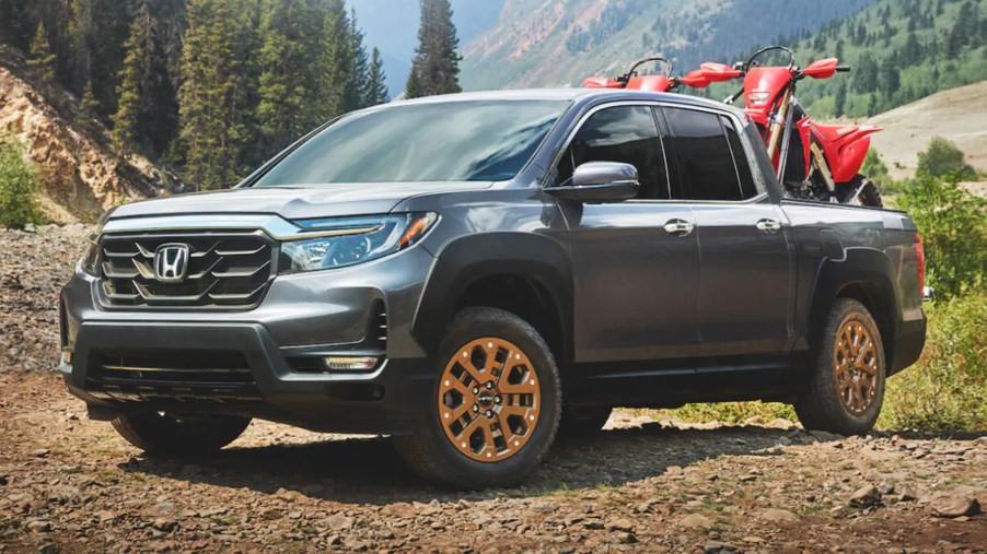 all-new 2022 Honda Ridgeline posing off-road with two honda dirt bikes in the pickup bed