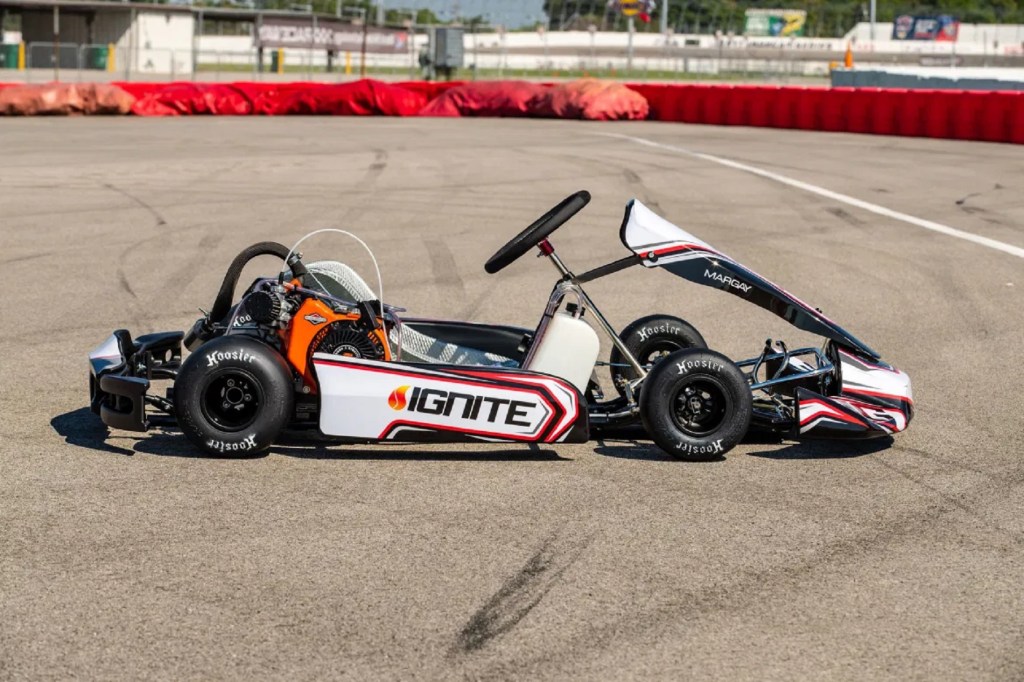 The side view of a white-red-and-black 2021 Ignite K3 racing kart on a racetrack
