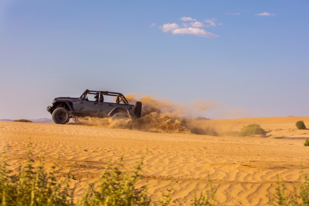 The 2021 Jeep Wrangler easily navigates a sand dune and is great for beach adventures