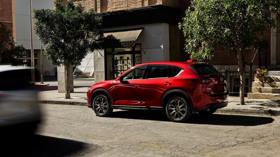 A red metallic 2021 Mazda CX-5 compact SUV parked on a city street on a sunny day
