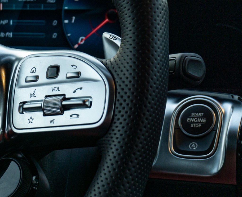 A close-up of the steering wheel, start button, and start-stop system defeat button in a 2021 Mercedes-AMG GLB 35