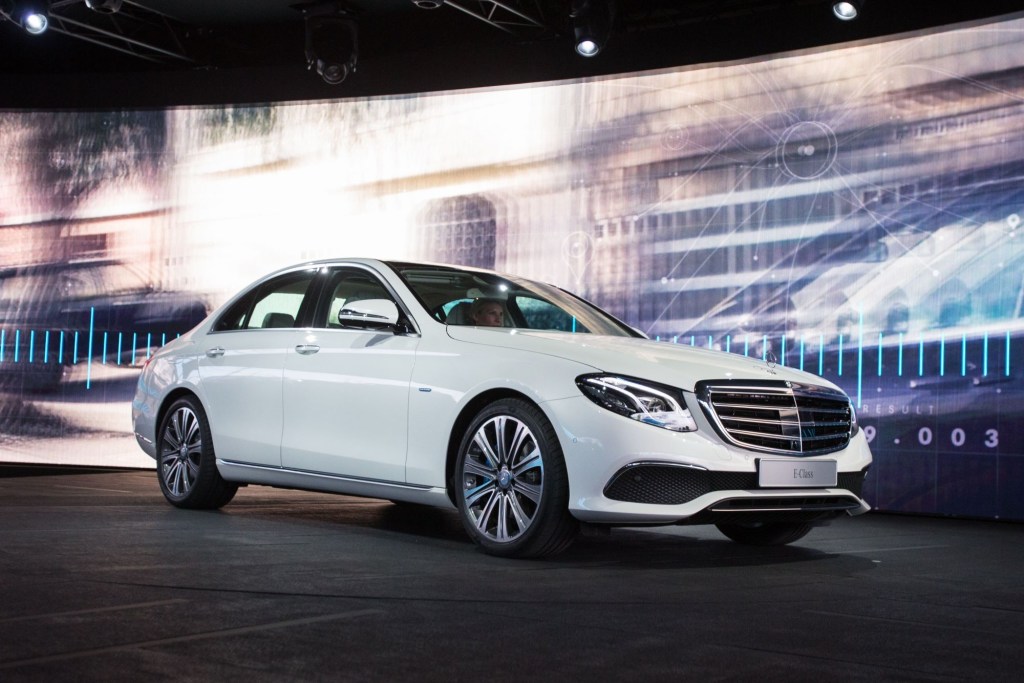 A white 2021 Mercedes-Benz E-Class sedan parked on a stage at an auto show