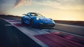 A blue 2021 Porsche 911 driving around a track, the 911 is the best new sports car for road trips