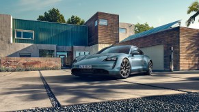 A light-blue 2021 Porsche Taycan electric sports car parked outside a modern home