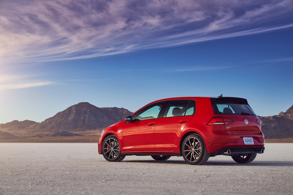 A red 2021 Volkswagen Golf GTI hatchback parked in a desert with mountains and blue sky