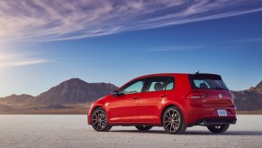 A red 2021 Volkswagen Golf GTI hatchback parked in a desert with mountains and blue sky
