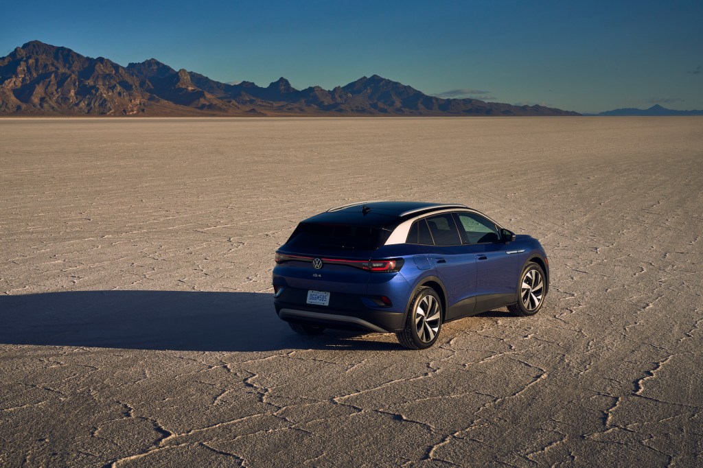 A blue metallic 2021 Volkswagen ID.4 Pro S electric SUV parked in a desert with mountains in the distance