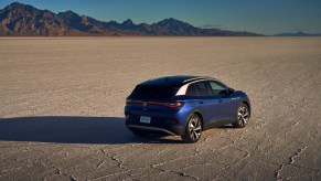 A blue metallic 2021 Volkswagen ID.4 Pro S electric SUV parked in a desert with mountains in the distance
