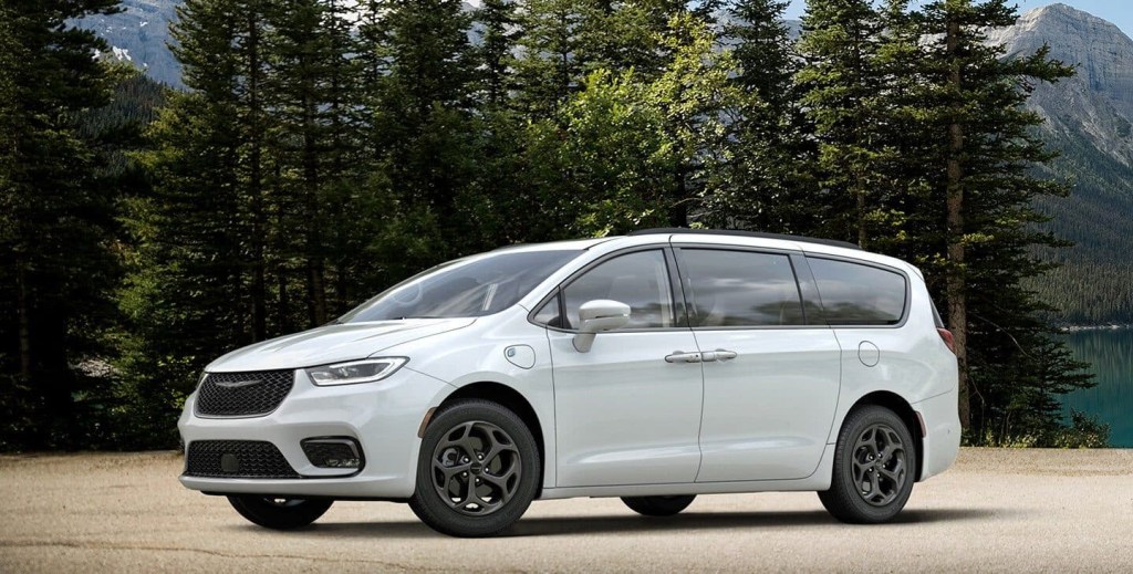 a white 2021 Chrysler Pacifica Hybrid parked outside in front of a scenic forested area